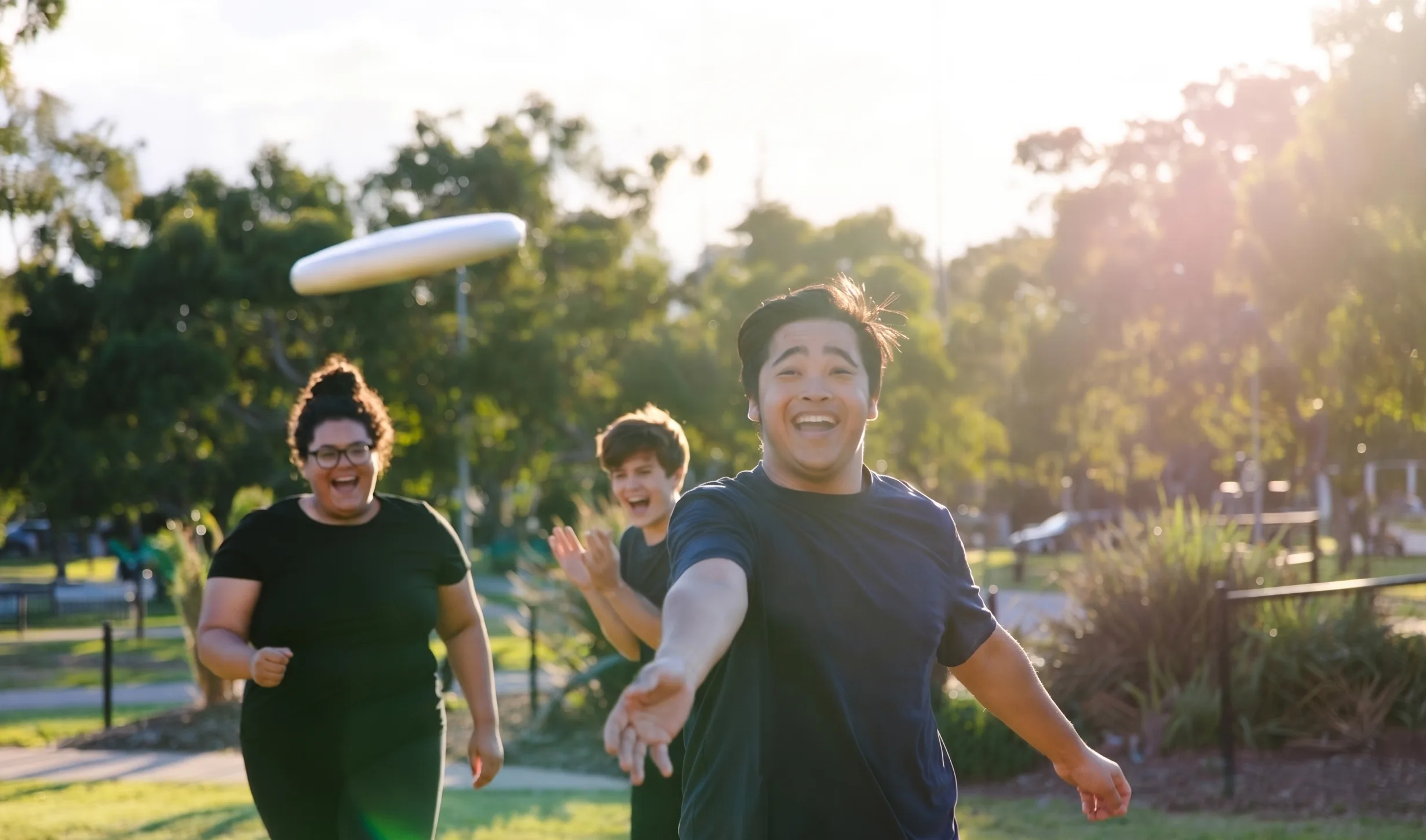 Participant and support worker walking beside sports courts in warm afternoon light