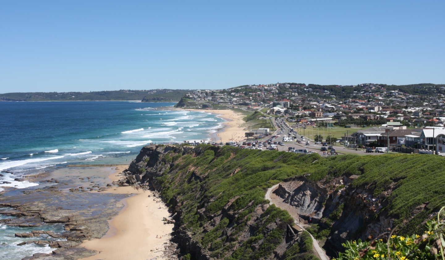 Bar Beach and the Newcastle coastline with sand, surf, cliffs, and ocean beyond