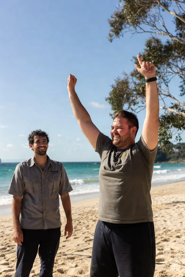 Participant celebrating on the beach with a support worker