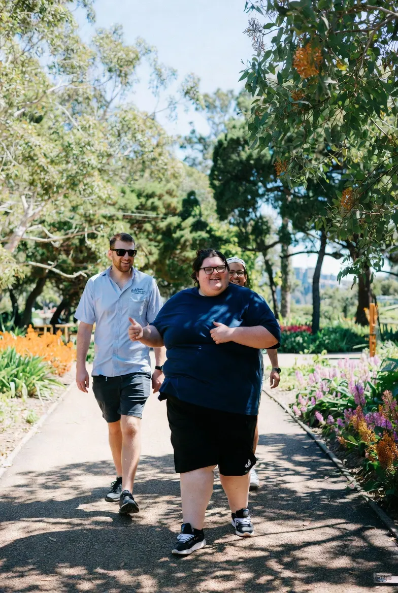 Three people walking together through a garden path